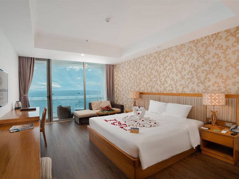 Phòng khách sạn sang trọng với giường cỡ lớn, trang trí romantic, ban công biển, ánh sáng tự nhiên.