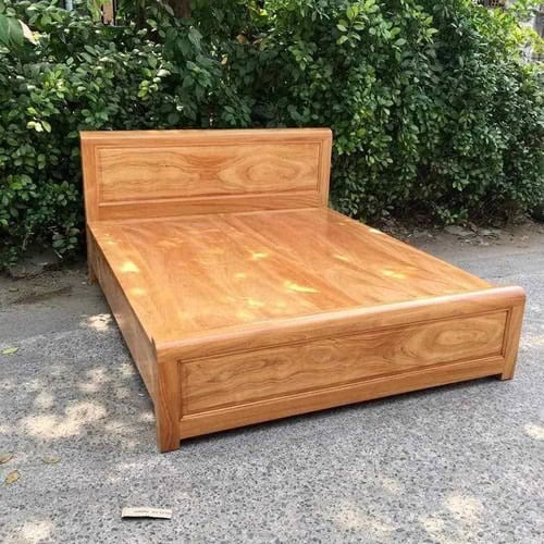 Giường gỗ tự nhiên đẹp, chắc chắn, đặt ngoài trời gần hàng rào cây xanh.