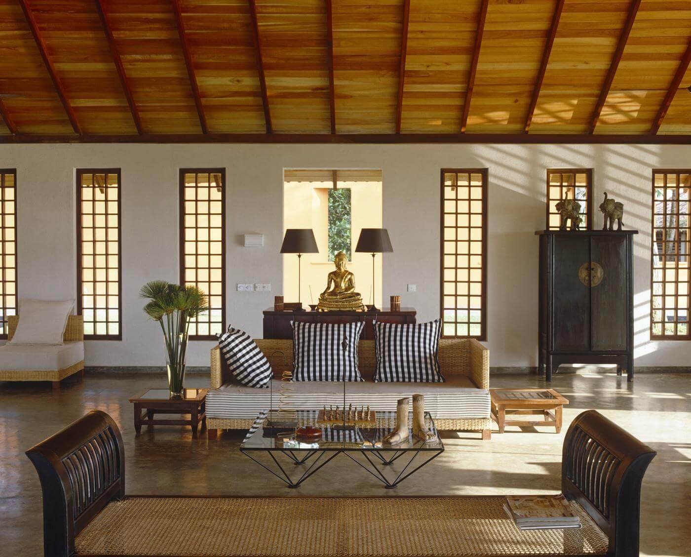 Phòng khách phong cách châu Á với tượng Phật, nội thất gỗ và ánh sáng tự nhiên, tạo không gian thư giãn.