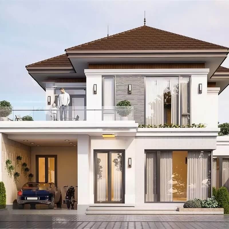 Ngôi biệt thự hiện đại hai tầng, mái ngói nâu, có gara và ban công, với người đứng tại ban công.