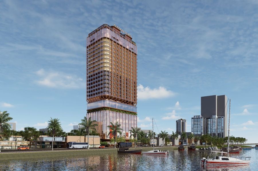 Tòa nhà cao tầng bên bờ sông với thuyền neo đậu, cảnh quan đô thị hiện đại và bầu trời xanh.