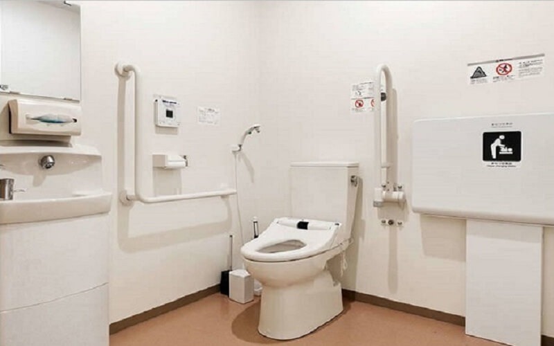 Phòng vệ sinh có bồn cầu hiện đại và thanh vịn dành cho người khuyết tật, đảm bảo tiện nghi và an toàn.