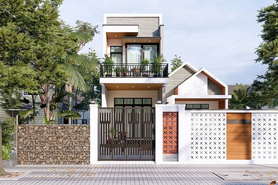 Nhà hai tầng hiện đại với ban công, cây xanh và hàng rào trước nhà, thiết kế đẹp mắt và thoáng mát.