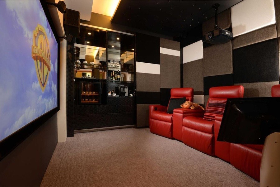 Phòng chiếu phim gia đình với ghế đỏ, màn hình lớn, thiết kế hiện đại và hệ thống âm thanh tiên tiến.