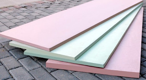 tam-xop-cach-nhiet-xps Tấm xốp cách nhiệt màu hồng và xanh lá, xếp chồng trên nền gạch xám, dùng trong xây dựng và cách âm.