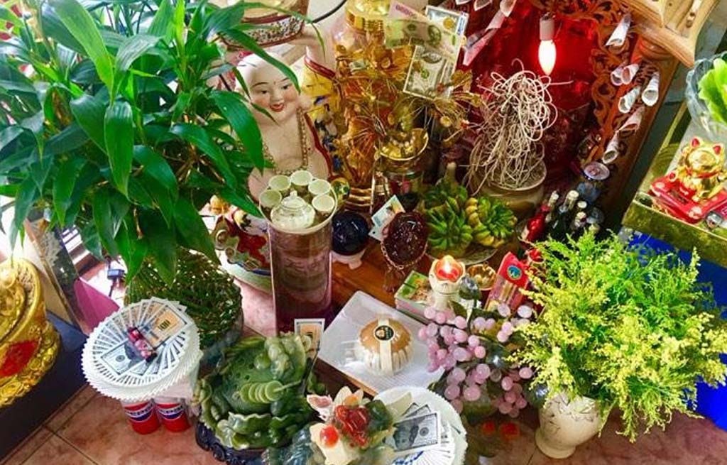 Bàn thờ Thần Tài Thổ Địa trang trí với cây xanh, hoa quả và tiền giấy, mang phong thuỷ tài lộc.