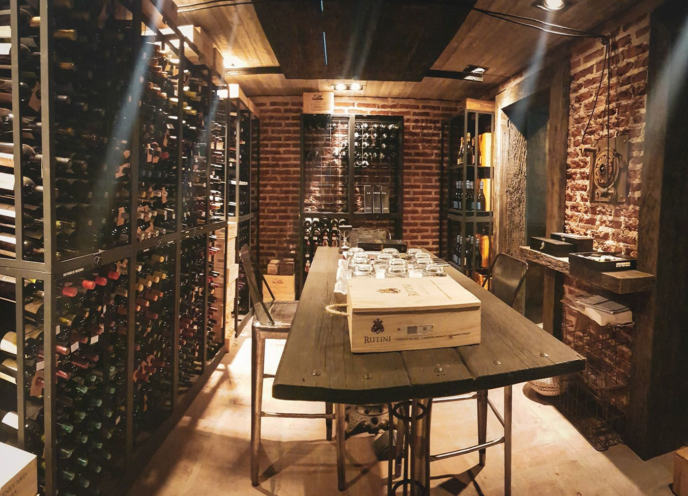 Hầm rượu vang tinh tế với kệ trưng bày chai rượu cạnh bàn gỗ, ánh sáng dịu trong không gian ấm cúng.