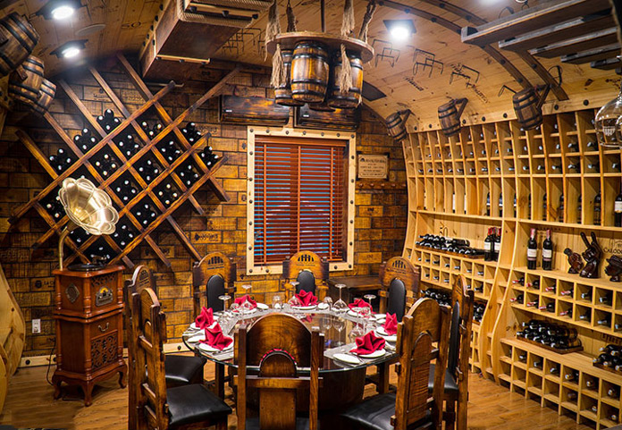 Hầm rượu vang sang trọng với bàn ăn và tủ rượu treo tường, không gian thấm đẫm sự ấm áp.