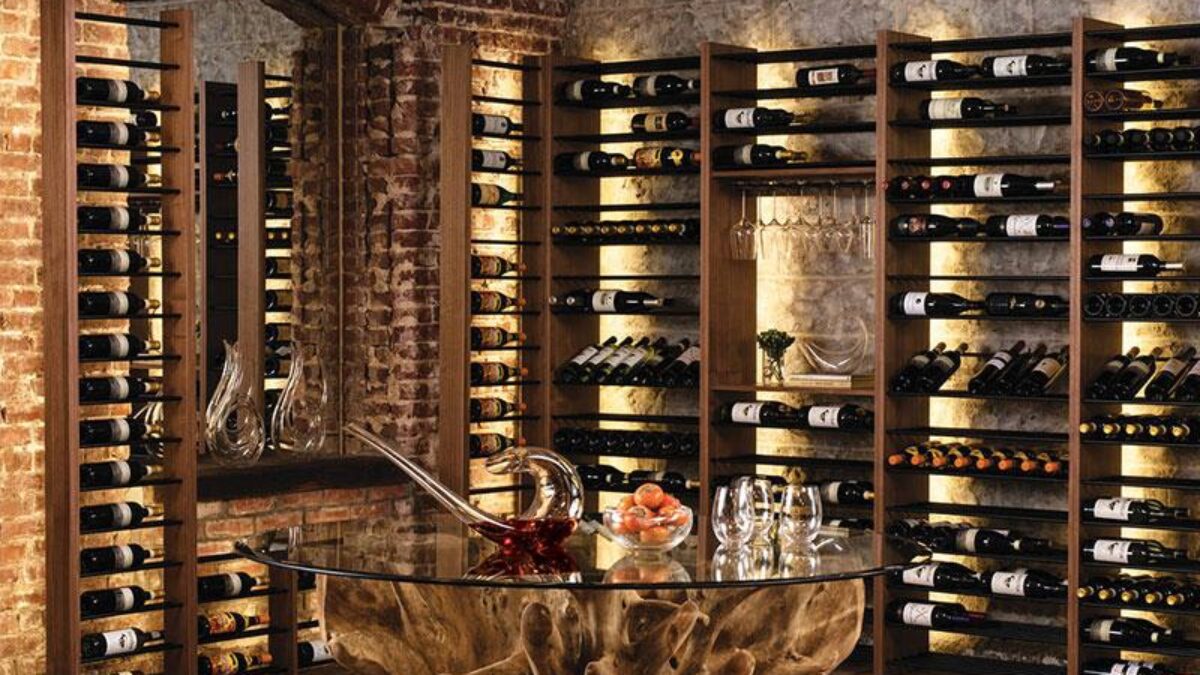 Hầm rượu sang trọng với kệ gỗ chứa đầy chai rượu và bàn trang trí hiện đại trong ánh sáng dịu dàng.
