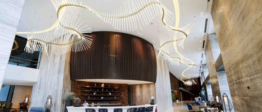 Sảnh khách sạn sang trọng với đèn chùm độc đáo và quầy lễ tân, nội thất hiện đại.