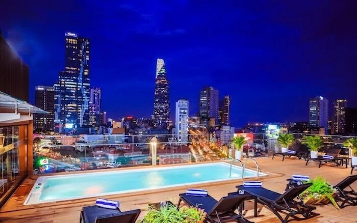 Hồ bơi sân thượng với thành phố về đêm ở TP.HCM, tòa nhà cao tầng lấp lánh tạo khung cảnh hiện đại và sôi động.