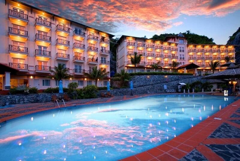 Khách sạn sang trọng với hồ bơi rộng rãi dưới ánh hoàng hôn, tạo không gian nghỉ dưỡng ấm áp và thư giãn.