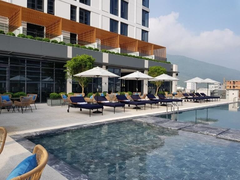 Khung cảnh hồ bơi sang trọng tại khách sạn, có ghế nằm và ô che nắng, tạo không gian thư giãn lý tưởng.