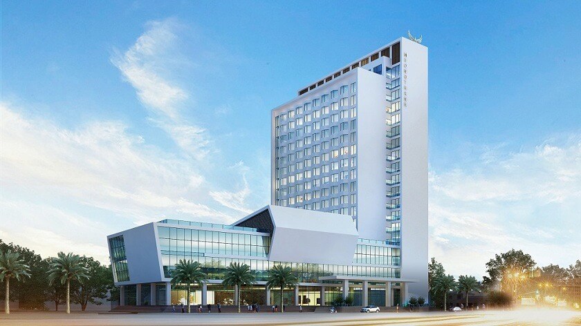 Tòa nhà cao tầng hiện đại với kiến trúc đặc sắc dưới trời xanh, đường phố và hàng cây bên dưới.