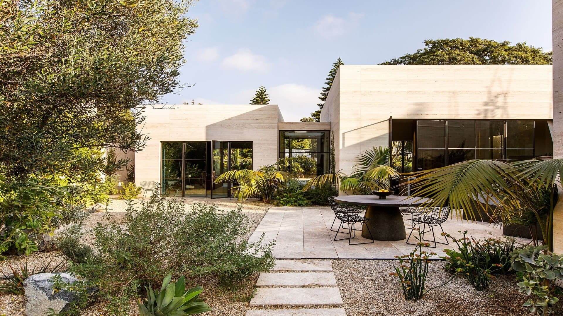 Biệt thự hiện đại giữa vườn xanh với bàn ghế ngoài trời, mang phong cách thiên nhiên và kiến trúc mở.