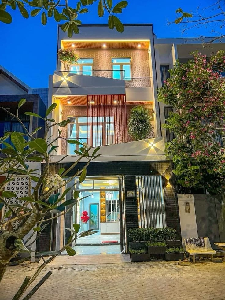 Nhà phố hiện đại với ánh đèn lung linh và cây xanh tươi mát vào buổi tối.