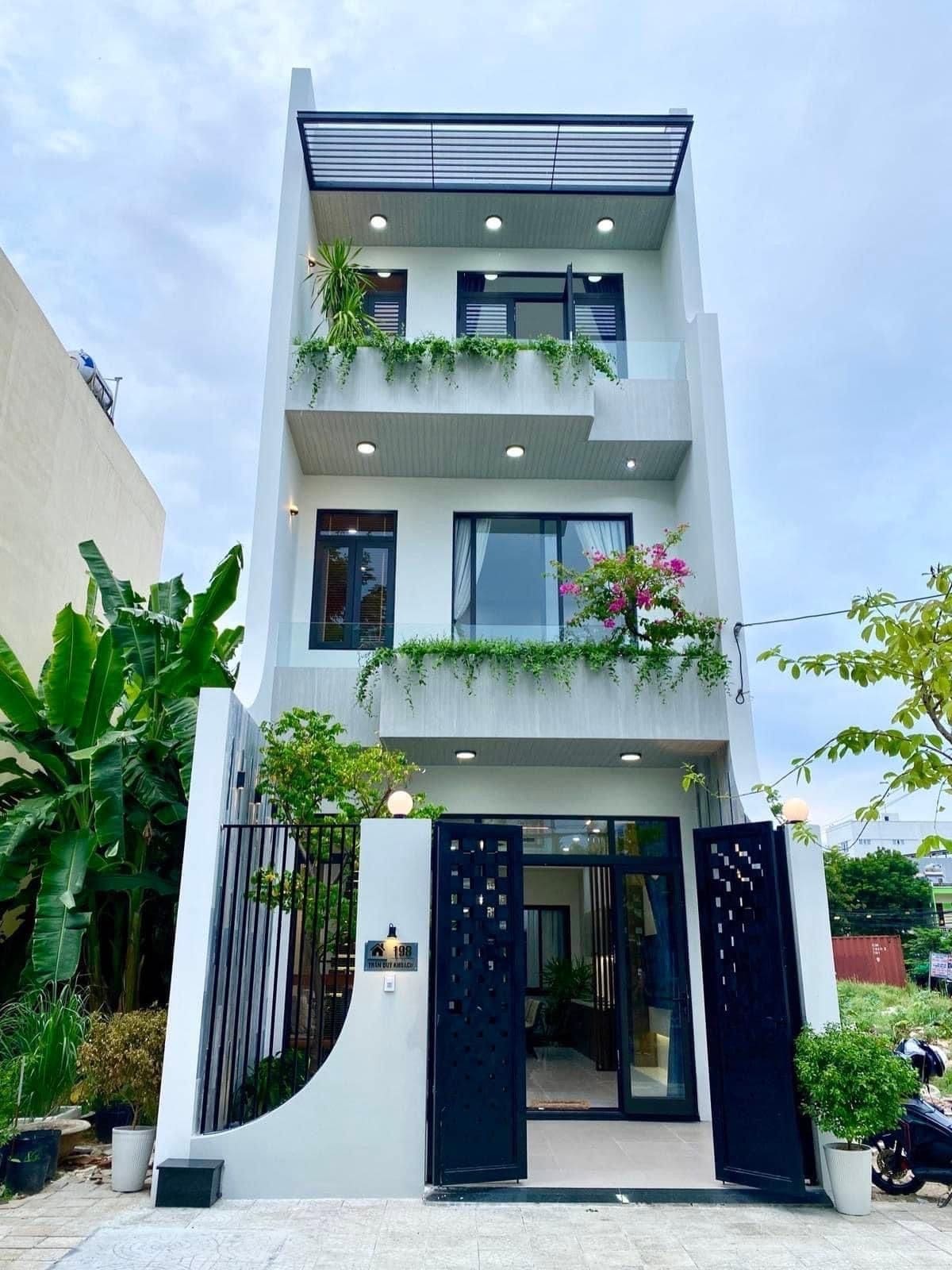 Nhà phố hiện đại ba tầng với cửa sổ kính và cây xanh trang trí, không gian sống thoáng mát.