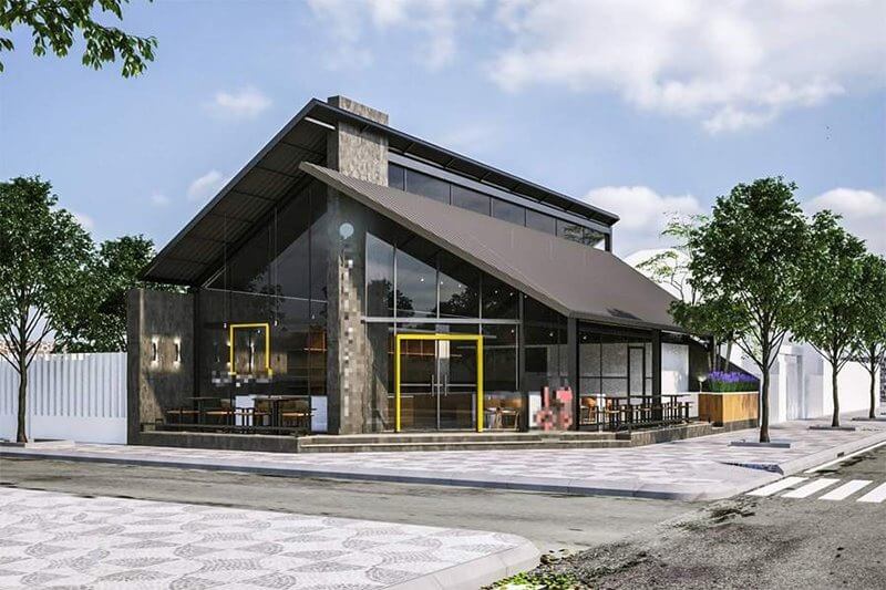 Tòa nhà thiết kế hiện đại với cửa kính lớn và mái nghiêng, nằm trên góc đường phố rợp bóng cây xanh.