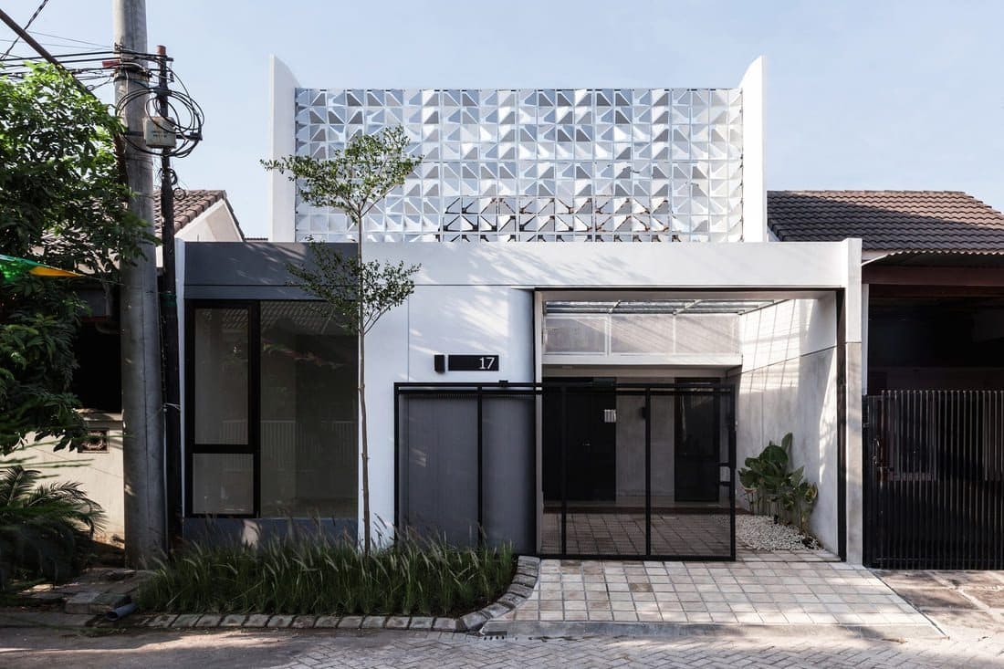 Nhà hiện đại với mặt tiền sáng tạo và cây xanh trước cửa, khu dân cư yên tĩnh.