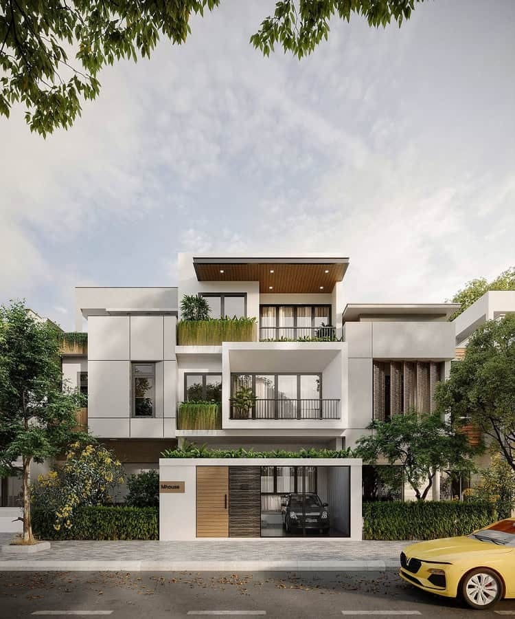 Nhà phố hiện đại với ba tầng, ban công rộng rãi, cây xanh và xe hơi đậu trước cổng.