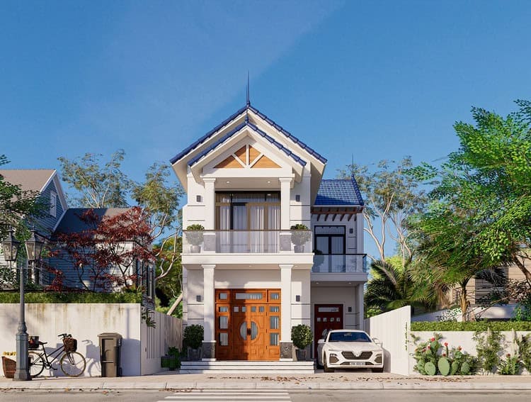 Nhà hai tầng mái ngói xanh, ban công kính, xe hơi trắng đậu trước cửa trong cảnh quan xanh mát.