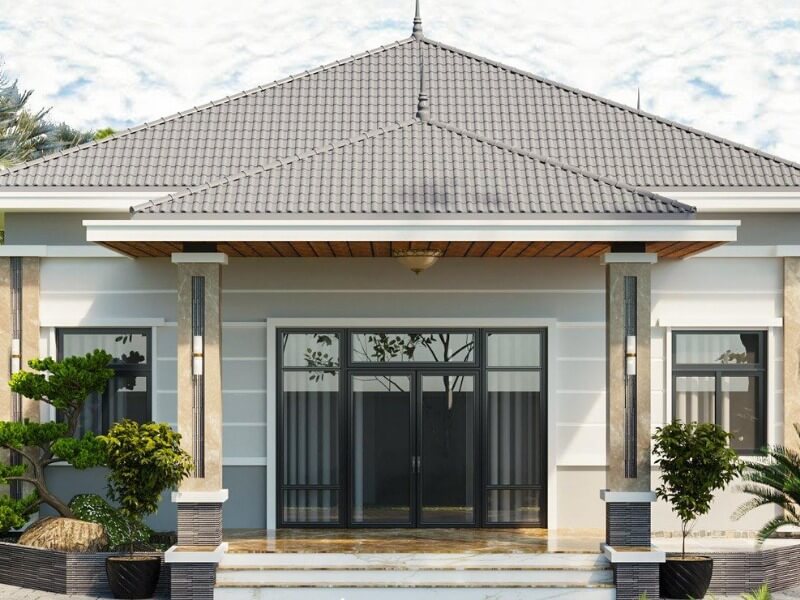 Nhà cấp 4 hiện đại với mái ngói xám, cột đá và cửa kính lớn, cây cảnh trước nhà.