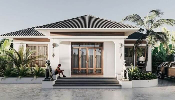 Nhà cấp 4 hiện đại, mái ngói, sân rộng, cây cọ và xe hơi, có người ngồi trước cửa.