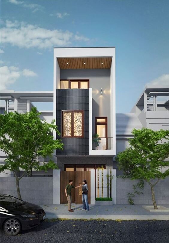 Nhà ống hiện đại 3 tầng, hai người đứng trước cổng, cây xanh hai bên, bầu trời trong xanh.