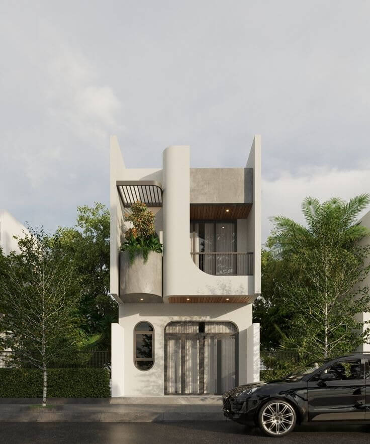 Nhà hiện đại hai tầng với ban công, cây xanh và xe hơi đen đậu trước, giữa cảnh quan xanh mát.