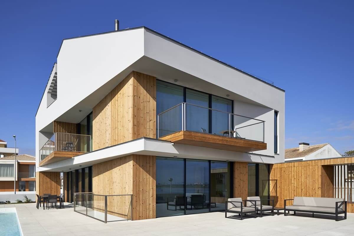 Biệt thự hiện đại với thiết kế gỗ và ban công rộng, bầu trời xanh trong nền.