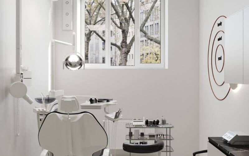 Phòng khám nha khoa hiện đại với ghế khám và trang thiết bị tối tân, có cửa sổ nhìn ra ngoài trời.