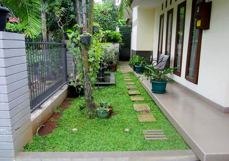 Khu vườn nhỏ gọn với cỏ xanh và lối đi đá bên cạnh ngôi nhà, tạo không gian thư giãn.