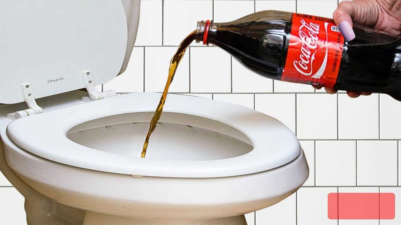 Người đổ chai Coca-Cola vào bồn cầu, có nắp bồn mở, trên nền tường ốp gạch trắng.