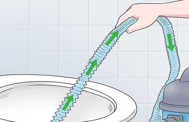 Có một người đang sử dụng máy hút bụi để thông tắc bồn cầu.