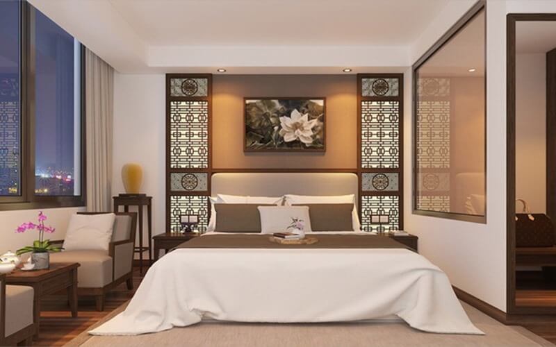 Phòng ngủ sang trọng với giường đôi, tranh hoa và cửa sổ lớn nhìn ra cảnh đêm thành phố.