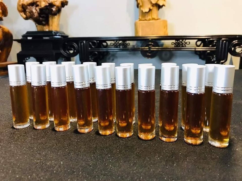 tinh-dau-tu-go-bach-xanh Hàng loạt chai dầu nước hoa màu nâu xếp trên bàn, nắp màu bạc, bối cảnh nội thất cổ điển.