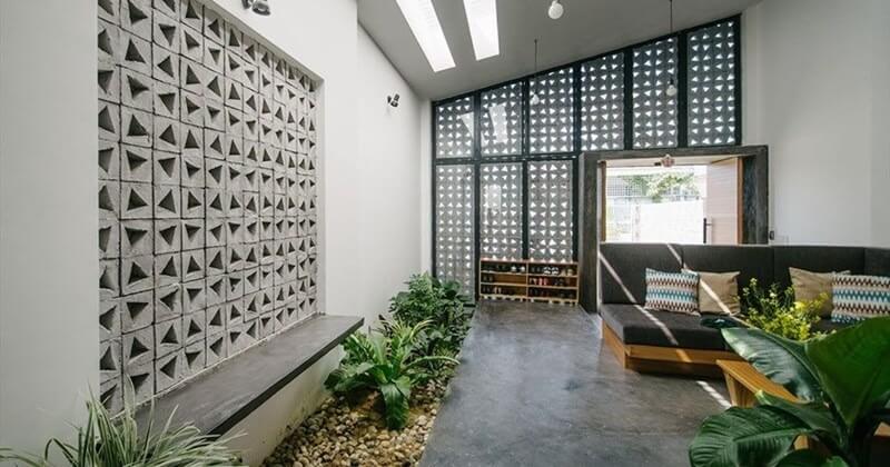 toi-uu-anh-sang-tu-nhien-cho-nha-6c39715 Phòng khách hiện đại với tường hoa văn, ghế sofa, cây xanh và ánh sáng tự nhiên từ cửa kính lớn.