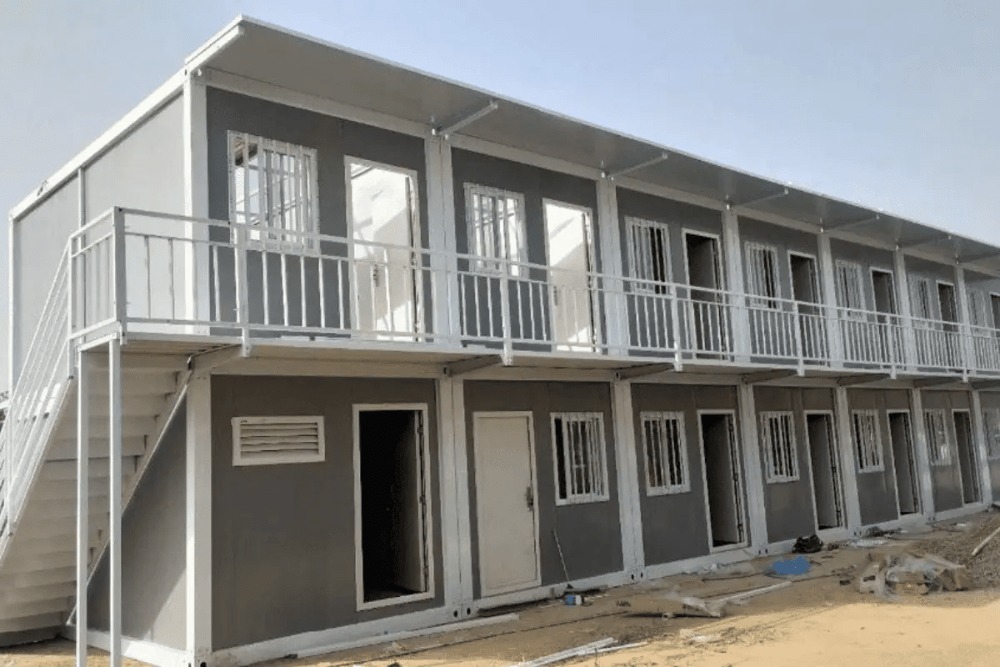 tong-chi-phi-xay-phong-tro-hai-tang-20m2 Dãy nhà lắp ghép hai tầng màu xám với cửa sổ và lan can trắng, thiết kế modul tiện lợi và hiện đại.