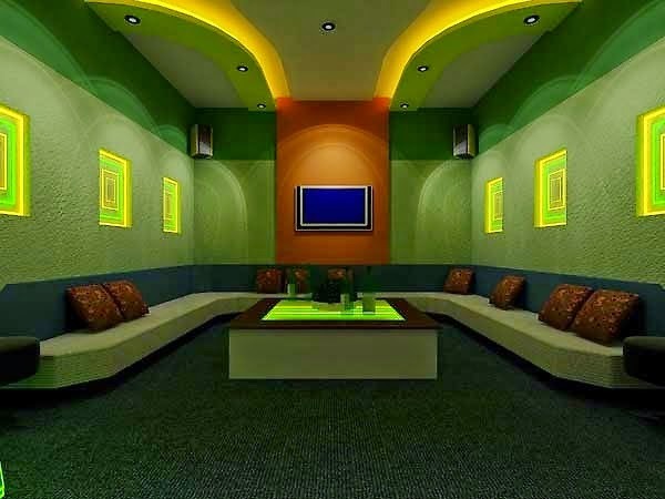 tran-thach-cao-cach-am-karaoke-3 Phòng karaoke hiện đại với đèn LED màu xanh và vàng, sofa dài và tivi treo tường.