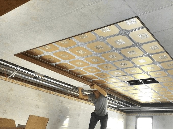 tran-thach-cao-chiu-nuoc Người đàn ông lắp đặt trần nhà với tấm ốp hoa văn tinh xảo, tạo không gian sang trọng và nghệ thuật.