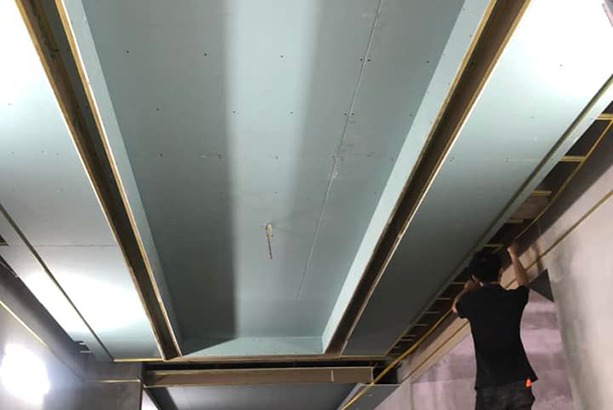 Thi công trần thạch cao hiện đại với người thợ đang lắp đặt khung xương cho trần nhà.