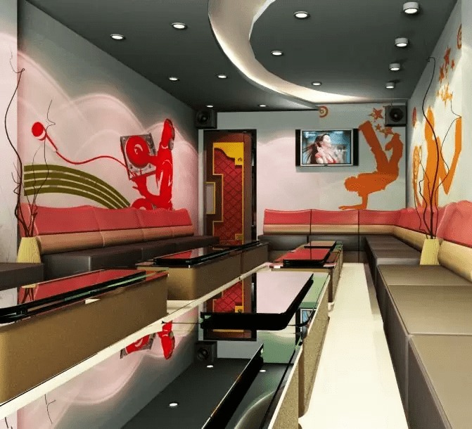 Phòng karaoke hiện đại với ghế sofa dài, bàn kính đen, tranh tường nghệ thuật và ánh sáng ấm cúng.