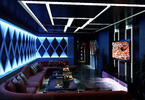 Phòng karaoke hiện đại với ánh sáng LED xanh, ghế sofa và màn hình lớn.
