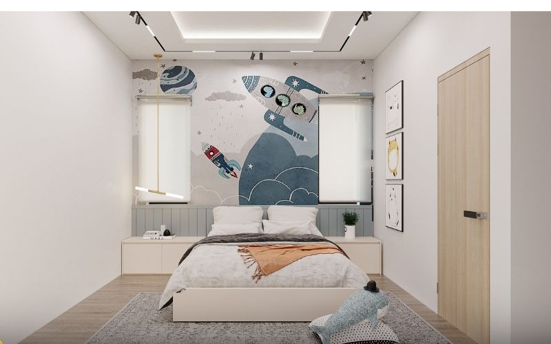 Phòng ngủ trẻ em trang trí hình tên lửa và phi hành gia, giường đôi với chăn màu xám, đèn trần sáng.