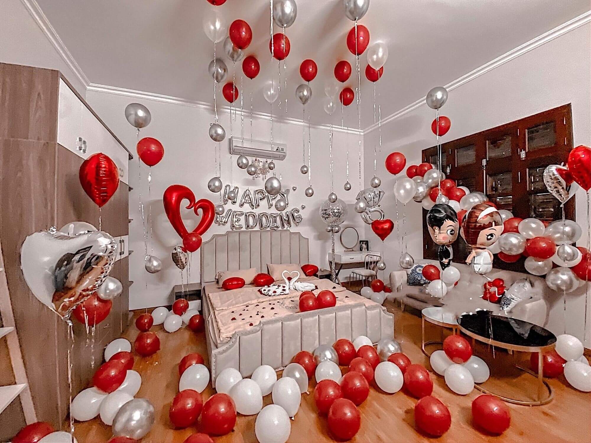 Trang trí phòng cưới với bóng bay đỏ, trắng và bạc, chữ Happy Wedding.