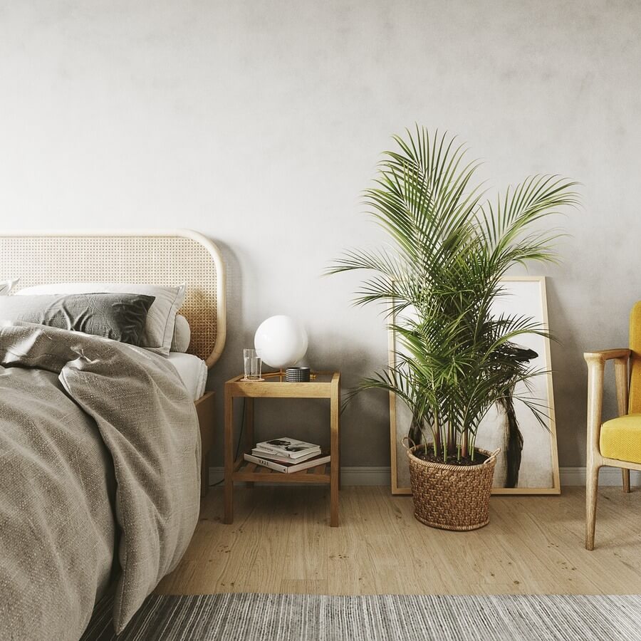 trang-tri-noi-that-trong-khong-gian-phong-ngu-scandinavian-1 Phòng ngủ hiện đại với cây xanh, giường êm ái, đèn bàn tròn và ghế màu vàng tạo không gian ấm cúng.