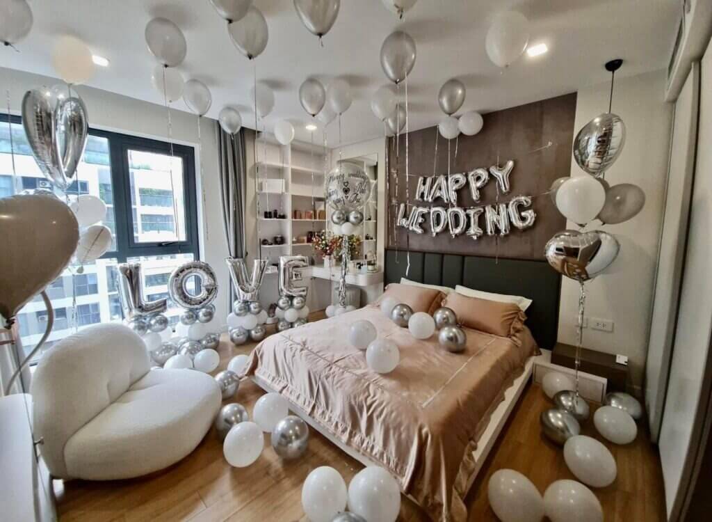 Phòng ngủ trang trí bóng bay cưới, chữ LOVE và HAPPY WEDDING, sắc trắng bạc tinh tế, lãng mạn.