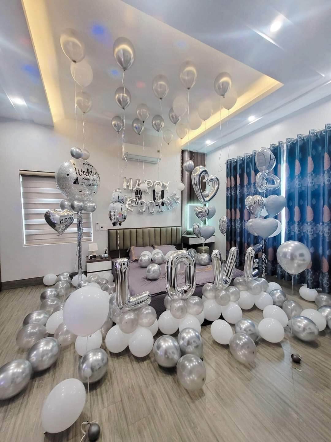 Trang trí phòng cưới với bóng bay bạc và trắng, chữ LOVE, tạo không gian lãng mạn và đẹp mắt.