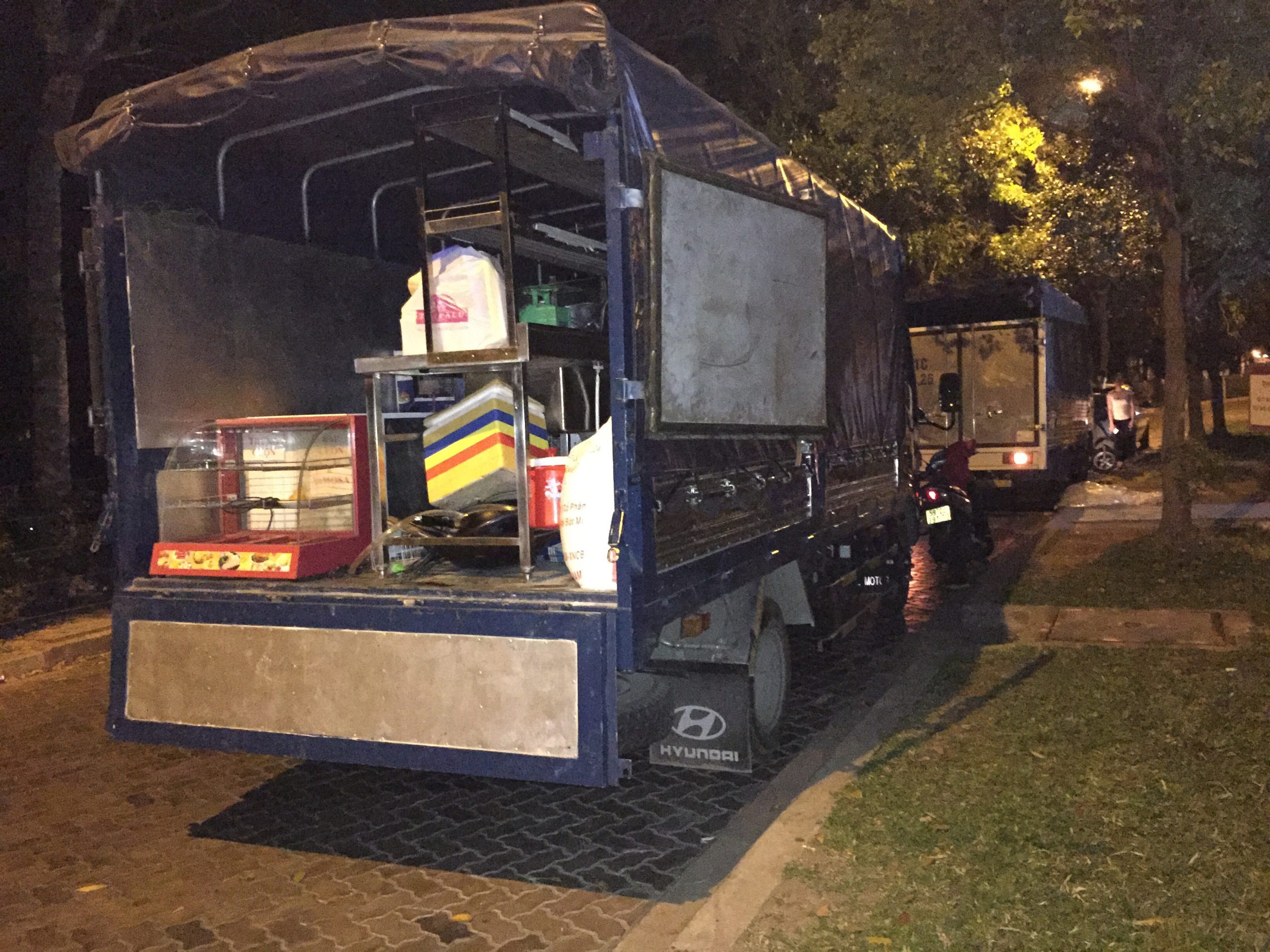 Xe tải đỗ bên đường vào ban đêm với đồ dùng nhà bếp phía sau, ánh sáng từ đèn đường chiếu sáng.