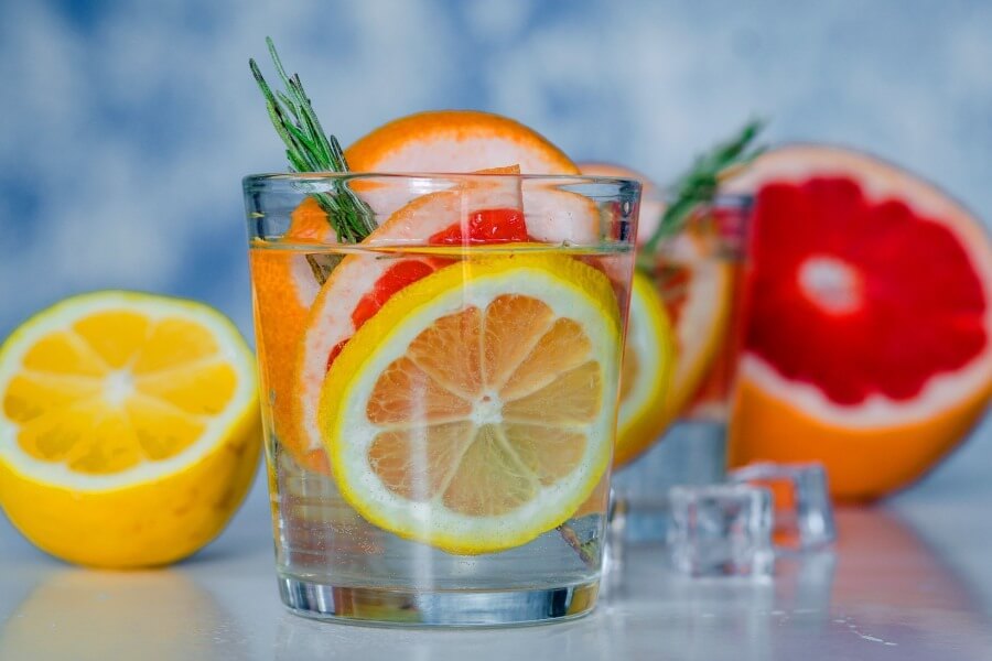 Ly nước trái cây tươi mát với lát chanh vàng, bưởi và lá thảo mộc, lý tưởng cho ngày hè nóng bức.